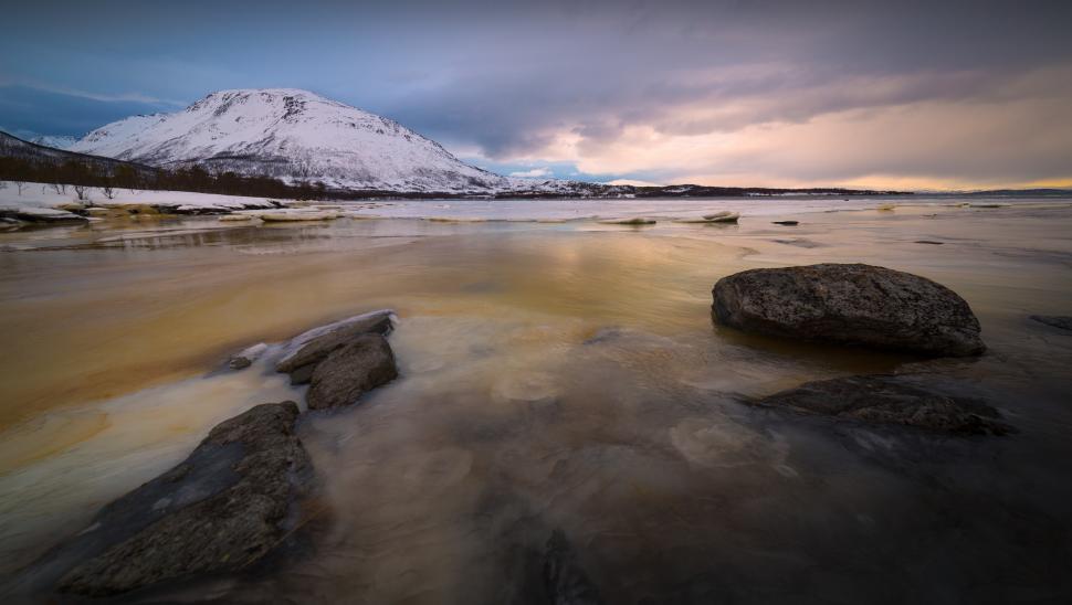 Free Image of A body of water with rocks and snow covered mountains 