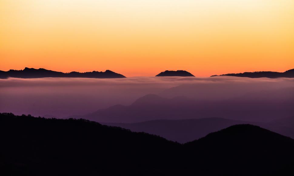 Free Image of A mountain range with clouds and orange sky 