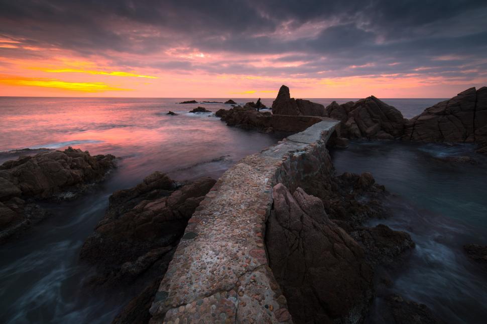 Free Image of A stone bridge over rocks in the ocean 
