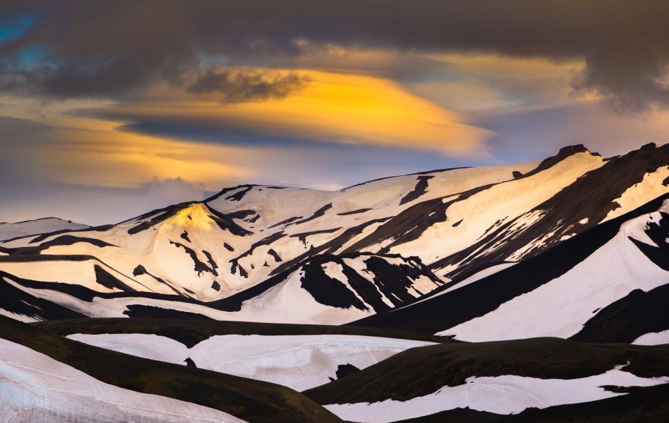 Free Image of Snow covered mountains with a yellow and grey sky 