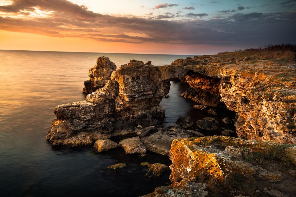Free Image of A rocky cliff with a bridge over water 