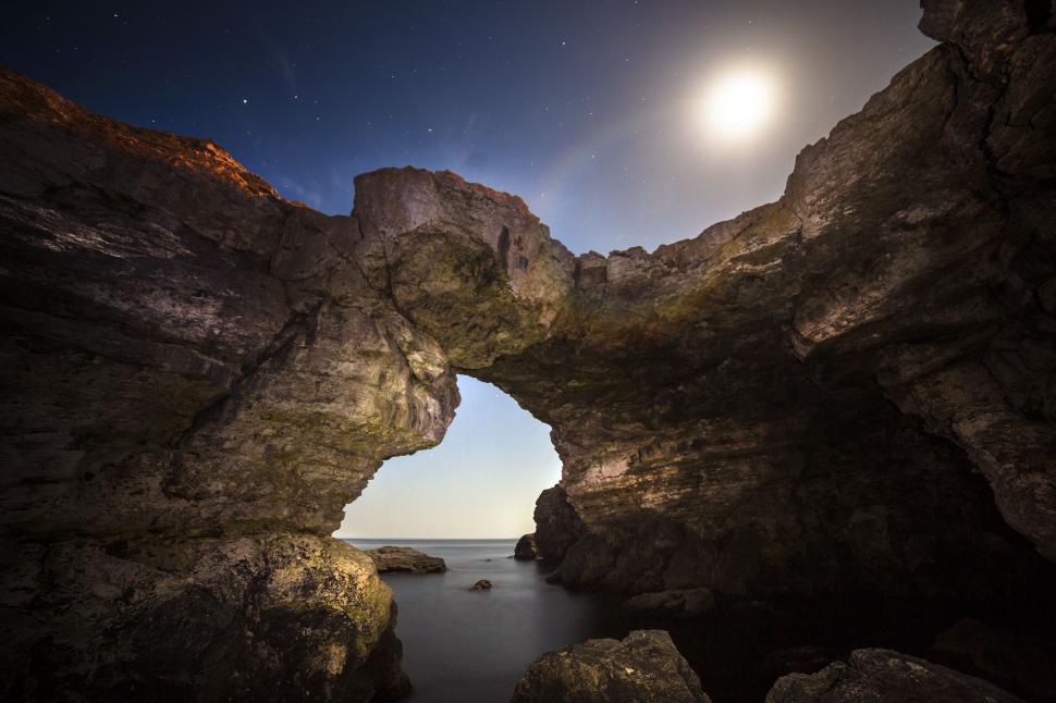 Free Image of A rock formation with a hole in the middle of the water 