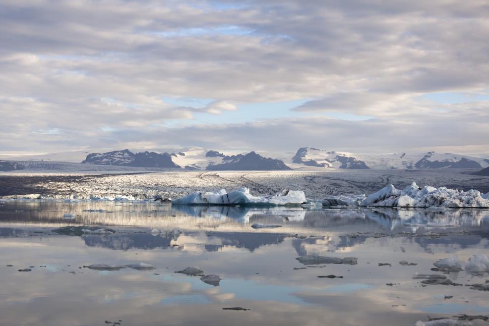 Free Image of A body of water with icebergs and mountains in the background 