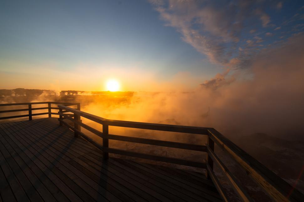 Free Image of A wooden deck with a railing overlooking a foggy landscape 