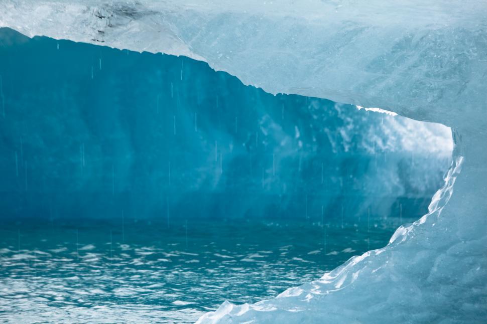 Free Image of A blue ice cave with water falling from it 