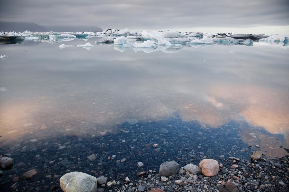 Free Image of A rocky shore with icebergs in the water 
