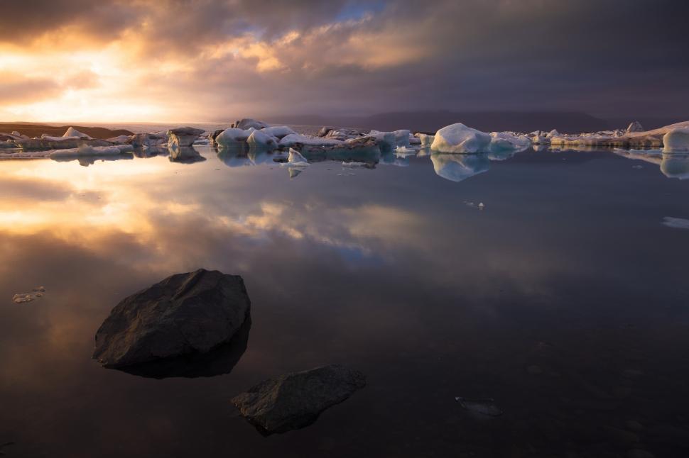 Free Image of A body of water with icebergs and rocks in it 