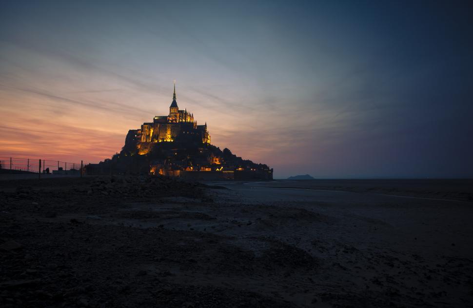 Free Image of A castle on a hill with lights with mont saint-michel in the background 