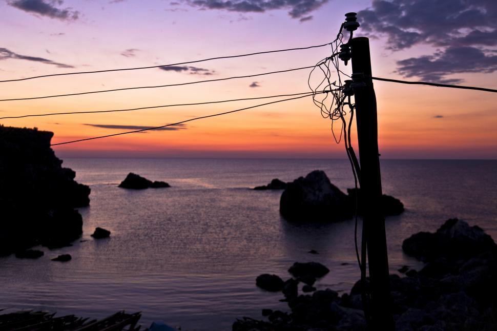 Free Image of A power lines on a pole with a sunset in the background 