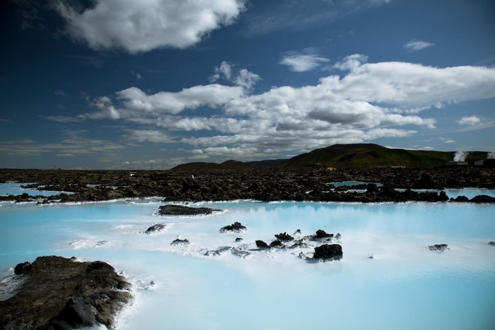 Free Image of A blue water with rocks and a hill in the background with blue lagoon in the background 
