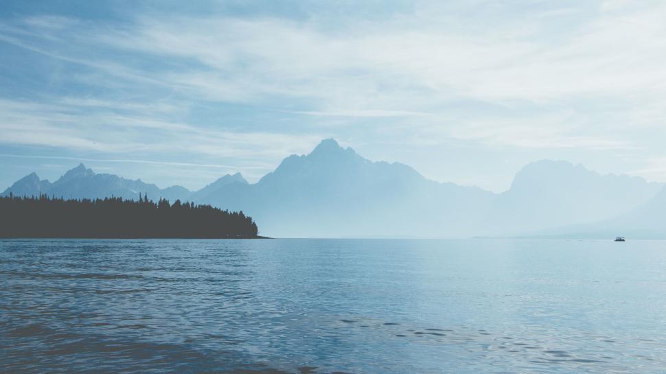 Free Image of A body of water with trees and mountains in the background 