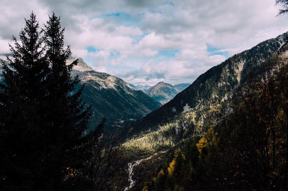 Free Image of A mountain range with trees and clouds 