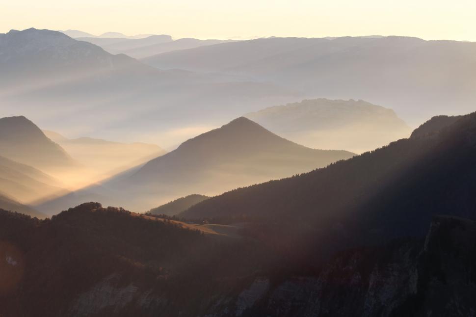 Free Image of A mountain range with sun rays coming through the mountains 