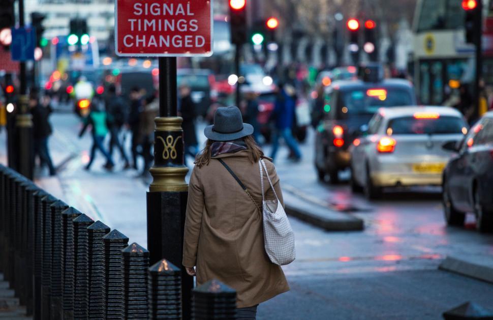 Free Image of A woman walking on a street with a sign 