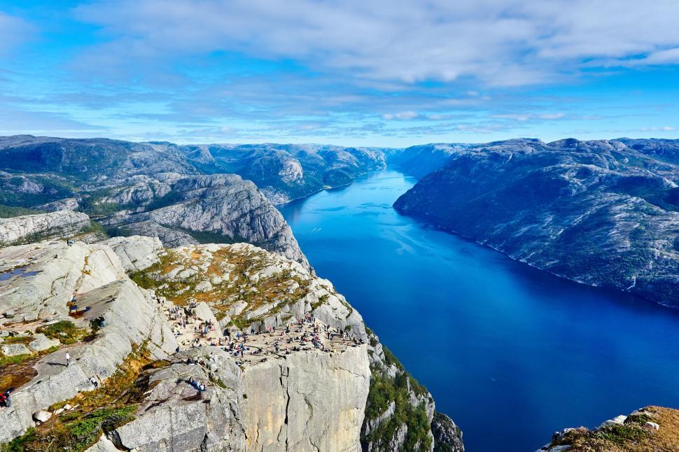 Free Image of A body of water next to a rocky cliff with preikestolen in the background 
