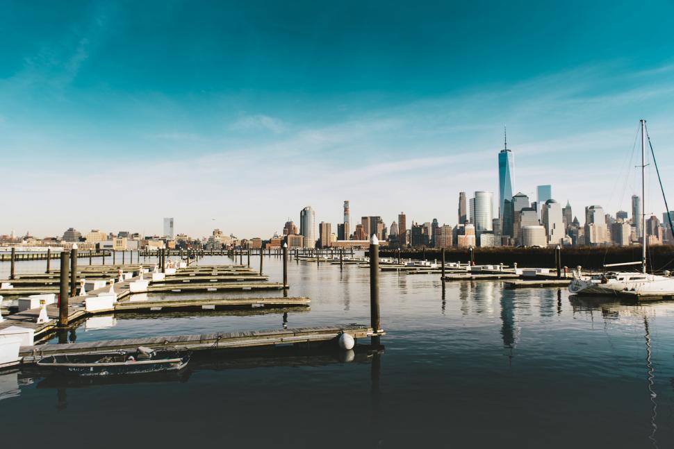 Free Image of A dock with boats in the water with a city in the background 