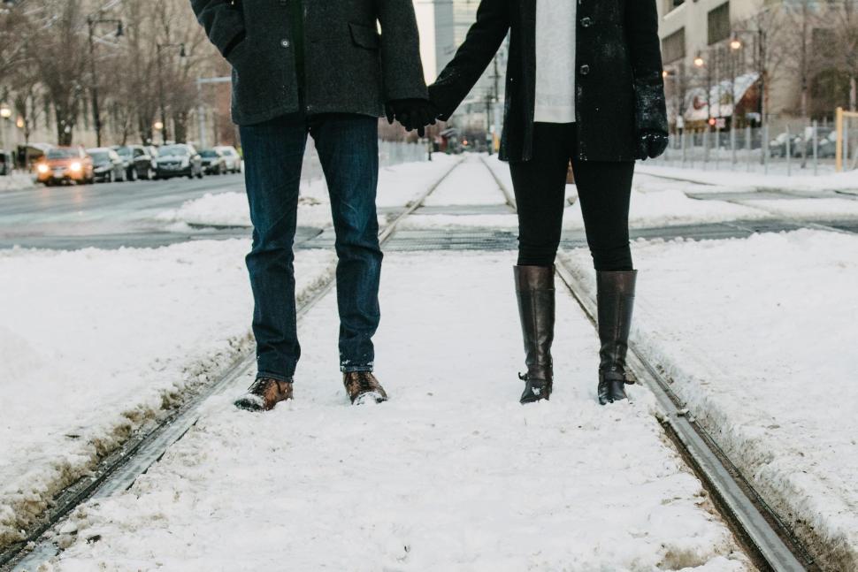 Free Image of A man and woman holding hands on a snowy street 