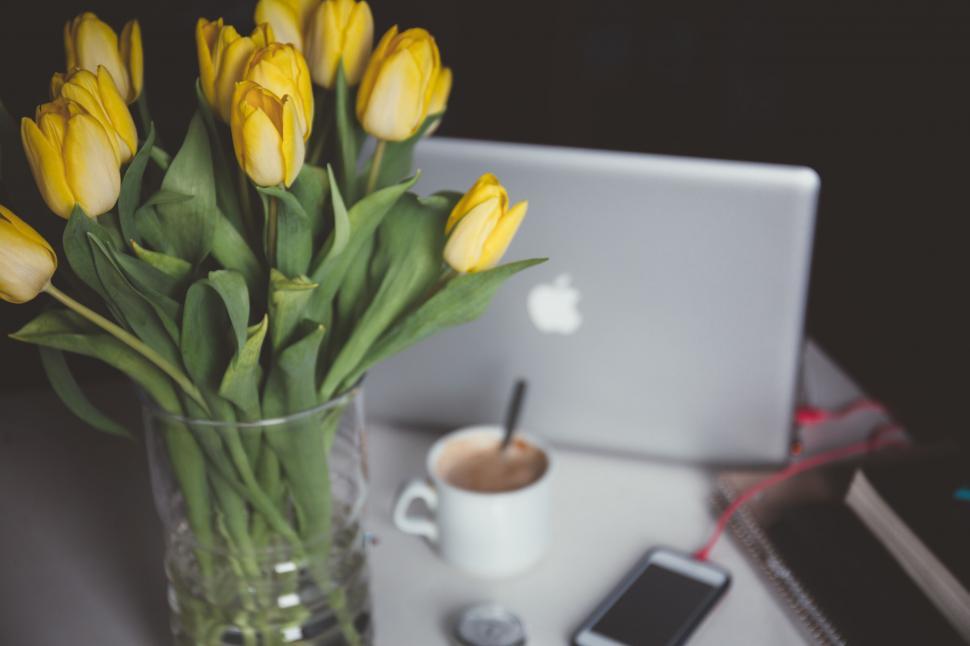 Free Image of A vase of yellow tulips and a cup of coffee on a table 