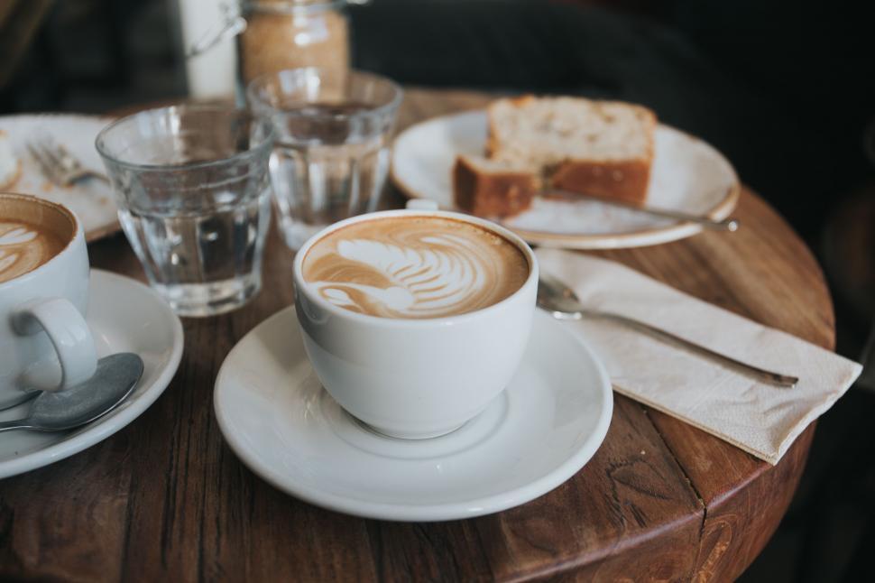 Free Image of A cup of coffee on a plate with bread and glasses 