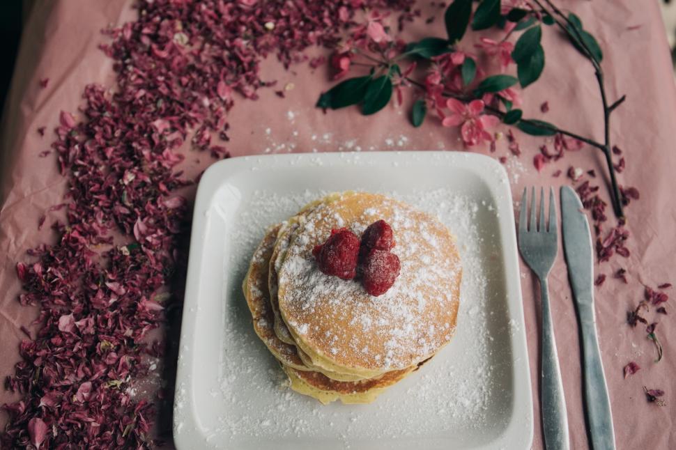 Free Image of A stack of pancakes with strawberries on top and powdered sugar on top 