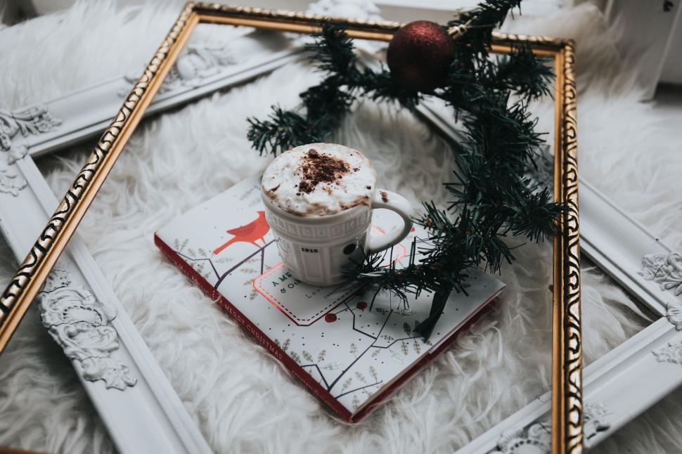Free Image of A cup of coffee on a book with a wreath in a frame 