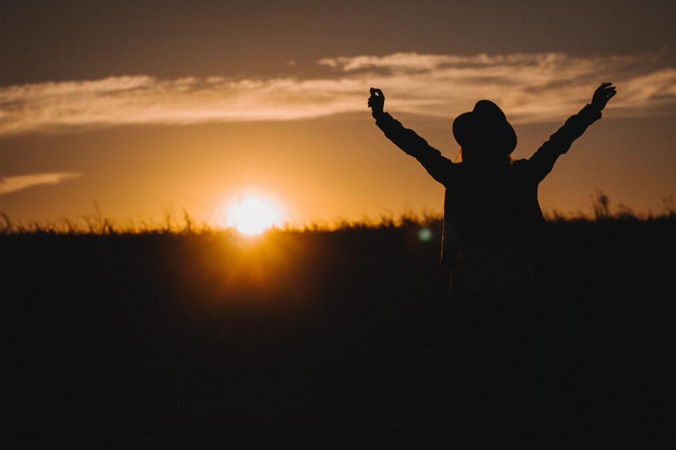 Free Image of A person standing in a field with their arms raised 