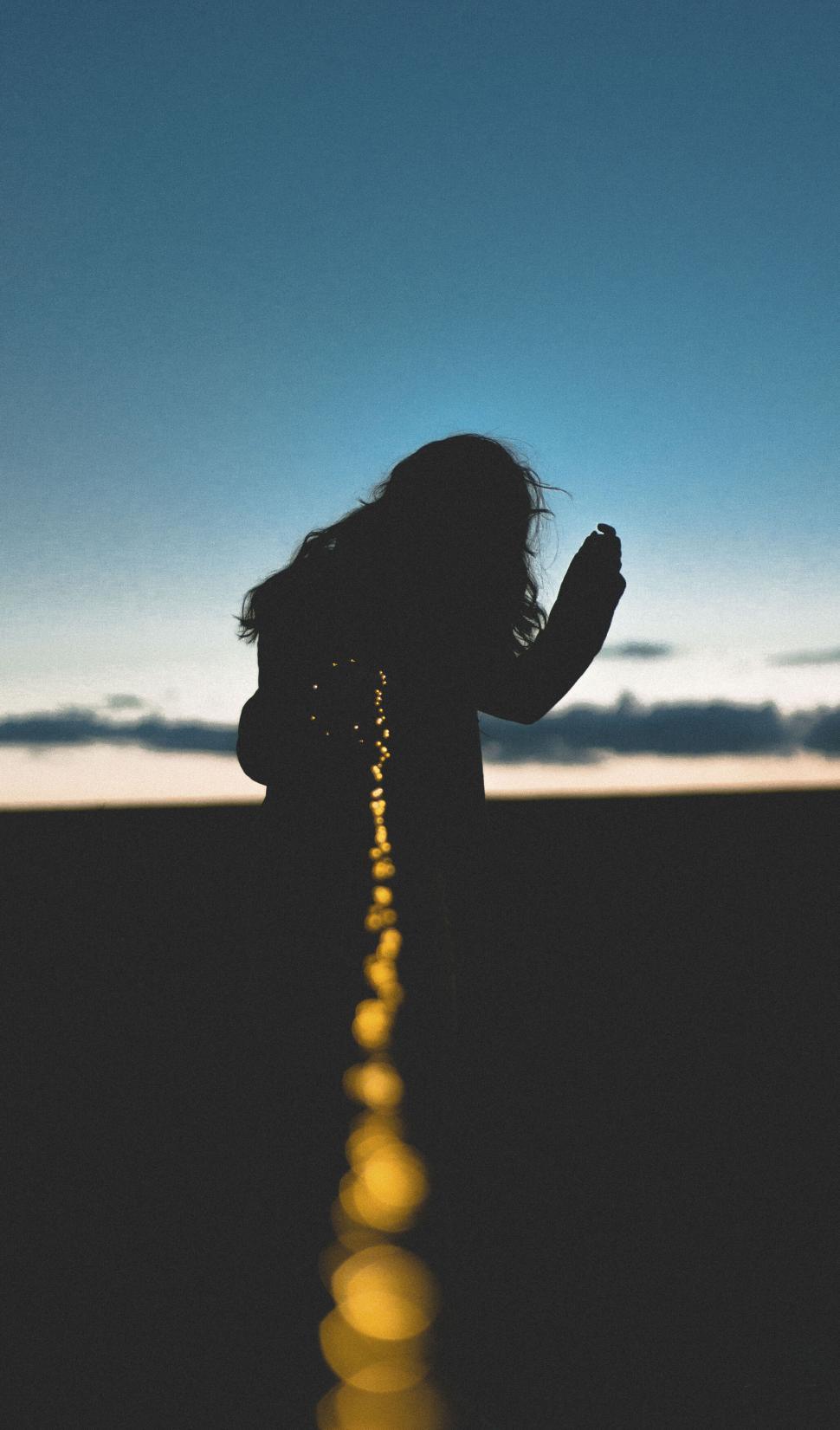Free Image of A silhouette of a woman holding a rope 