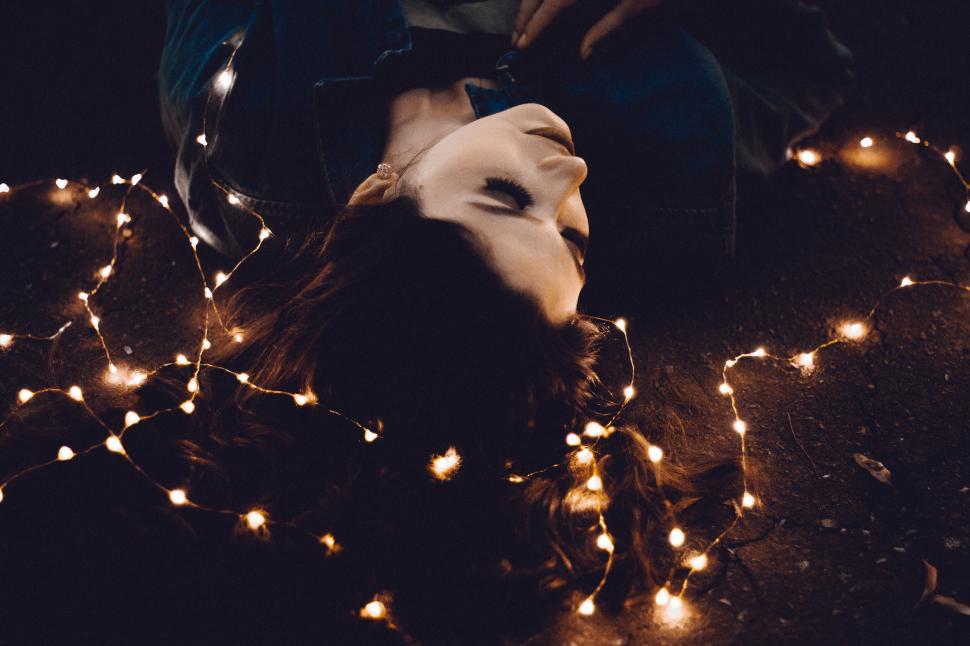 Free Image of A woman lying on the ground with lights around her 