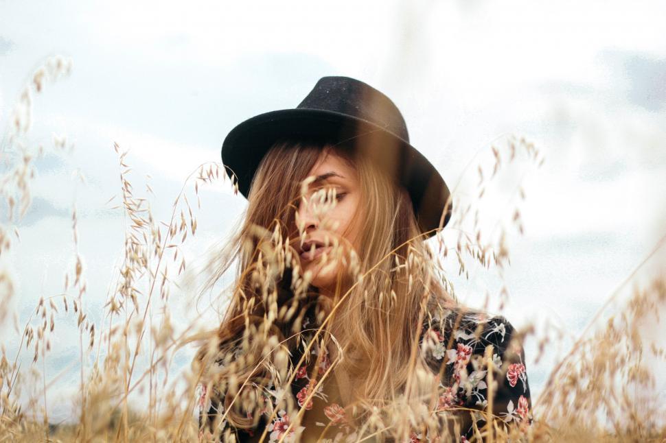 Free Image of A woman in a hat in a field of tall grass 