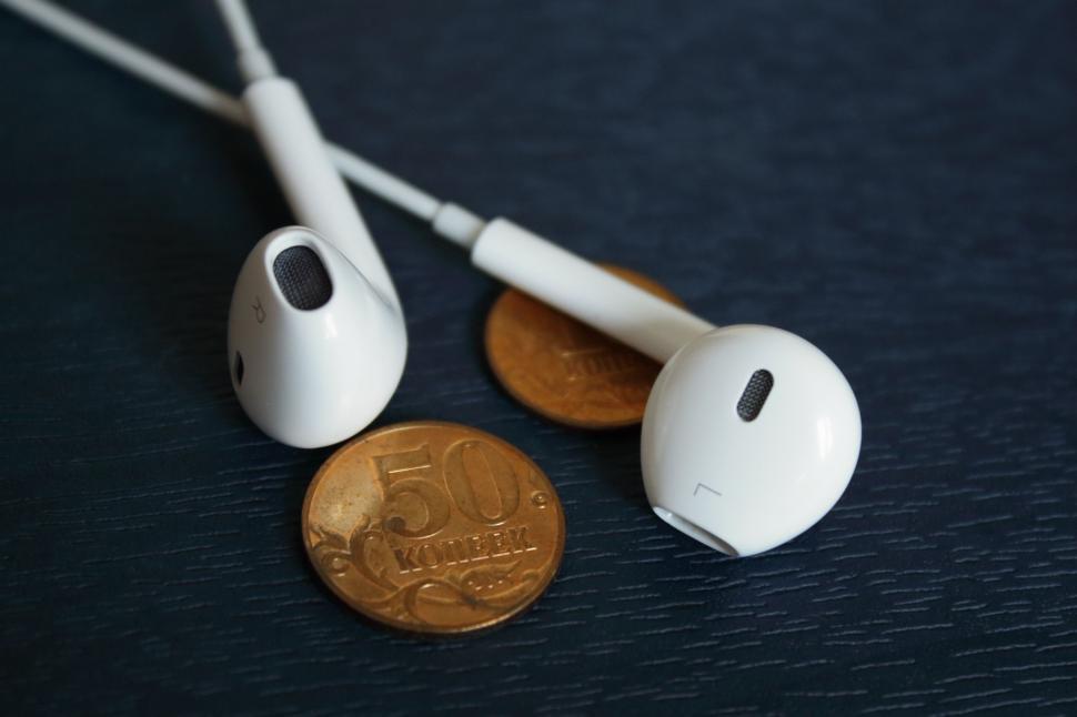 Free Image of A pair of white earphones next to a coin 