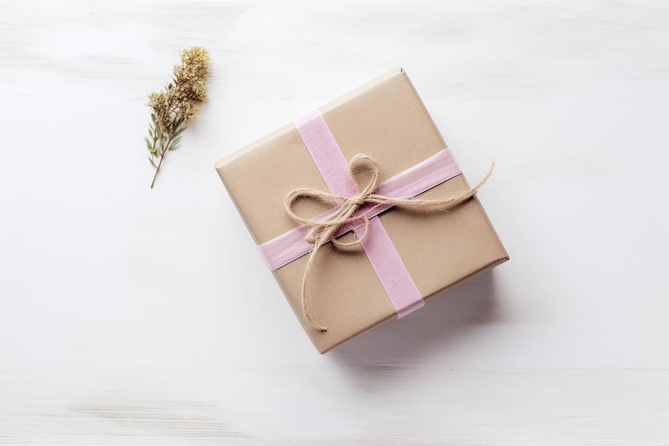 Free Image of A gift box with a pink ribbon and a small plant 