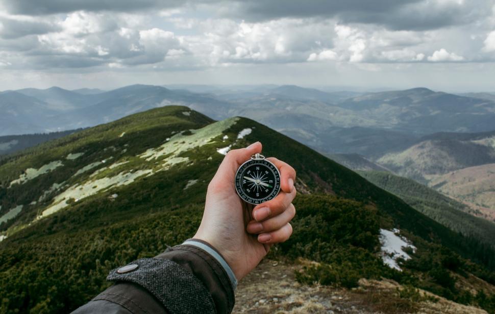 Free Image of A hand holding a compass on a mountain 