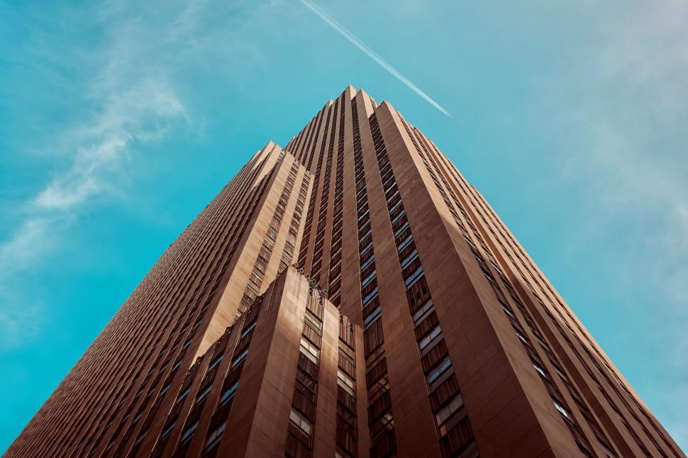 Free Image of A tall building with a jet trail in the sky 