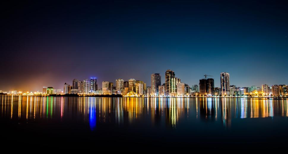Free Image of A city skyline with lights reflecting on water 