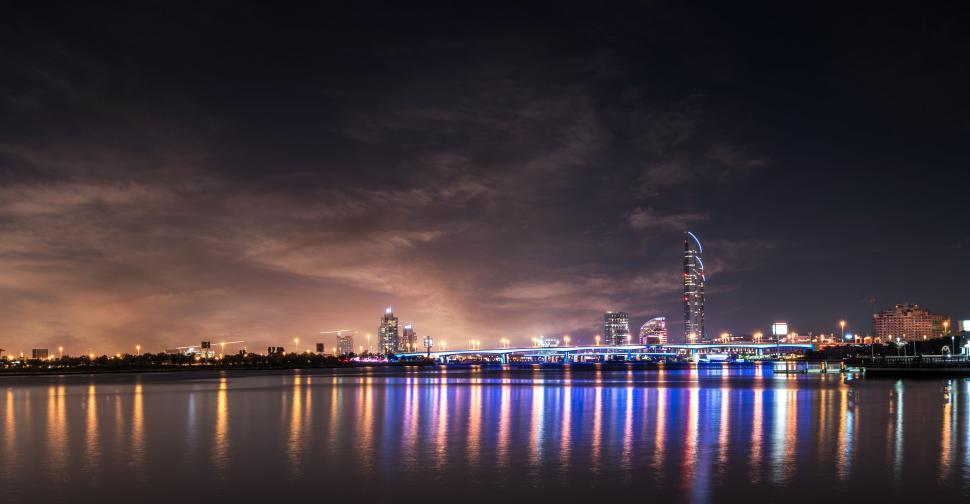 Free Image of A city skyline with lights reflecting on water 