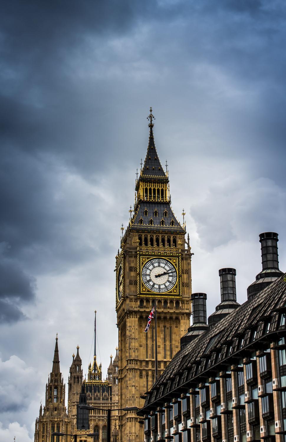 Free Image of A clock tower with a flag on top with big ben in the background 