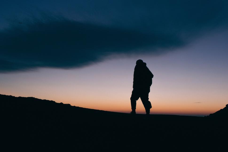 Free Image of A silhouette of a person walking on a hill 