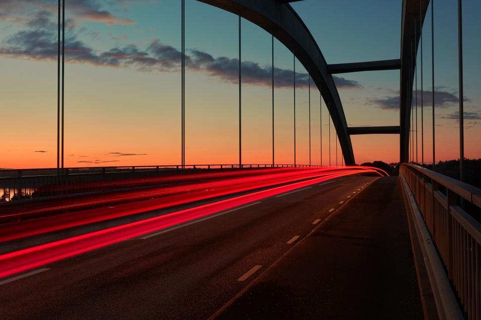 Free Image of A red light streaks on a bridge 