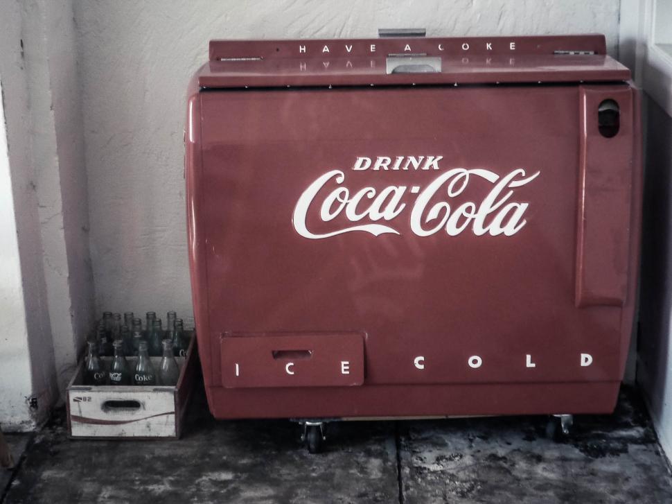 Free Image of A red refrigerator with white text and bottles in a box 
