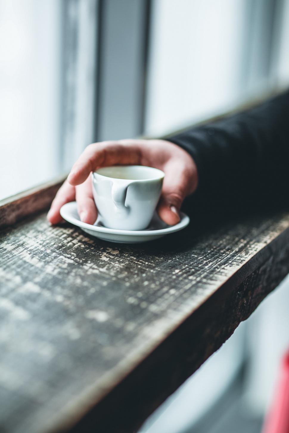 Free Image of A hand holding a cup and saucer 