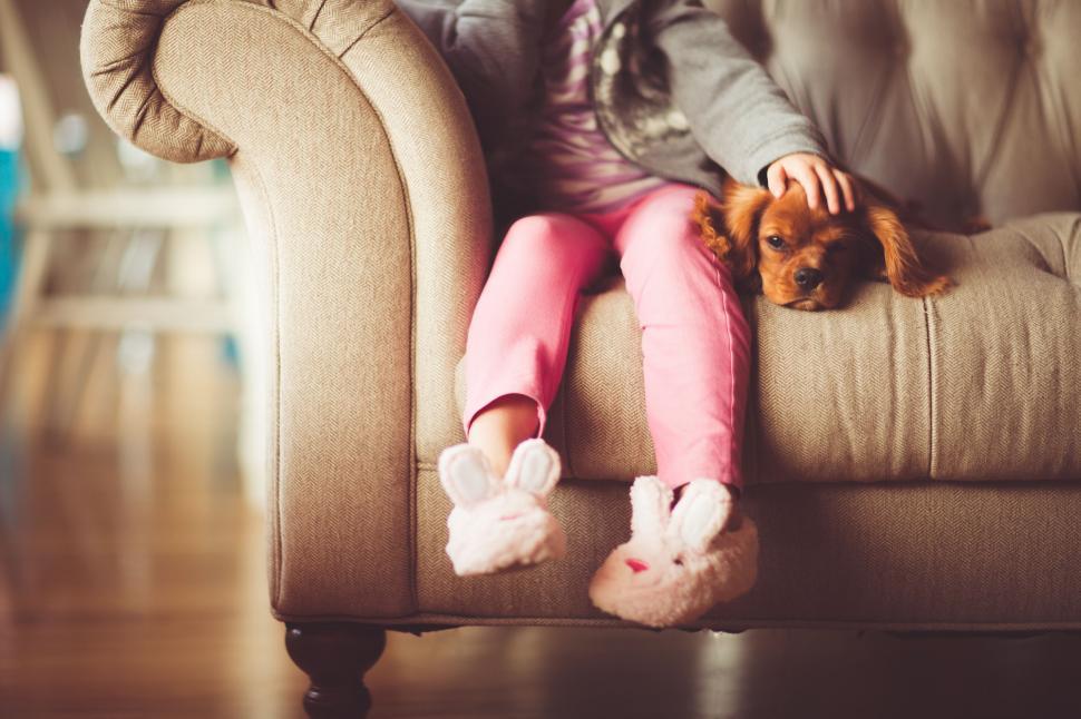 Free Image of A child sitting on a couch with a dog 