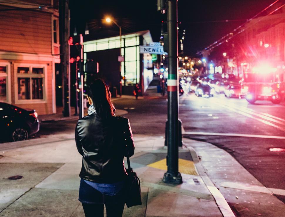Free Image of A woman standing on a sidewalk at night 