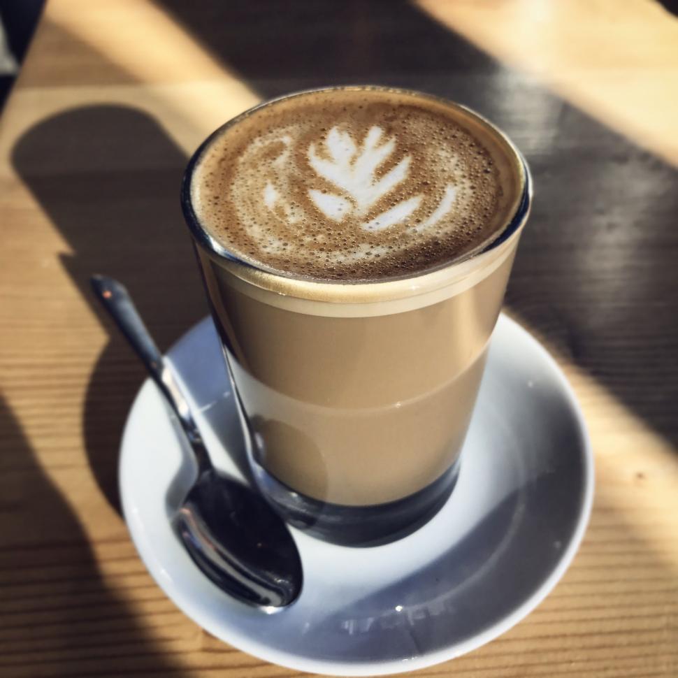Free Image of A cup of coffee with a leaf design on top of it 