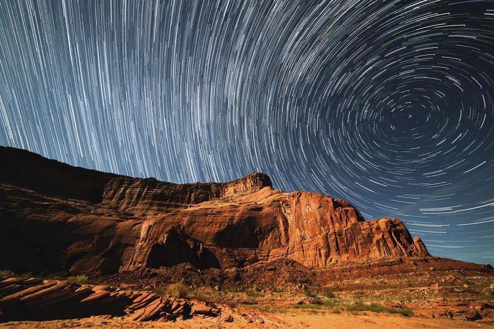 Free Image of A star trails in the sky over a rocky mountain 