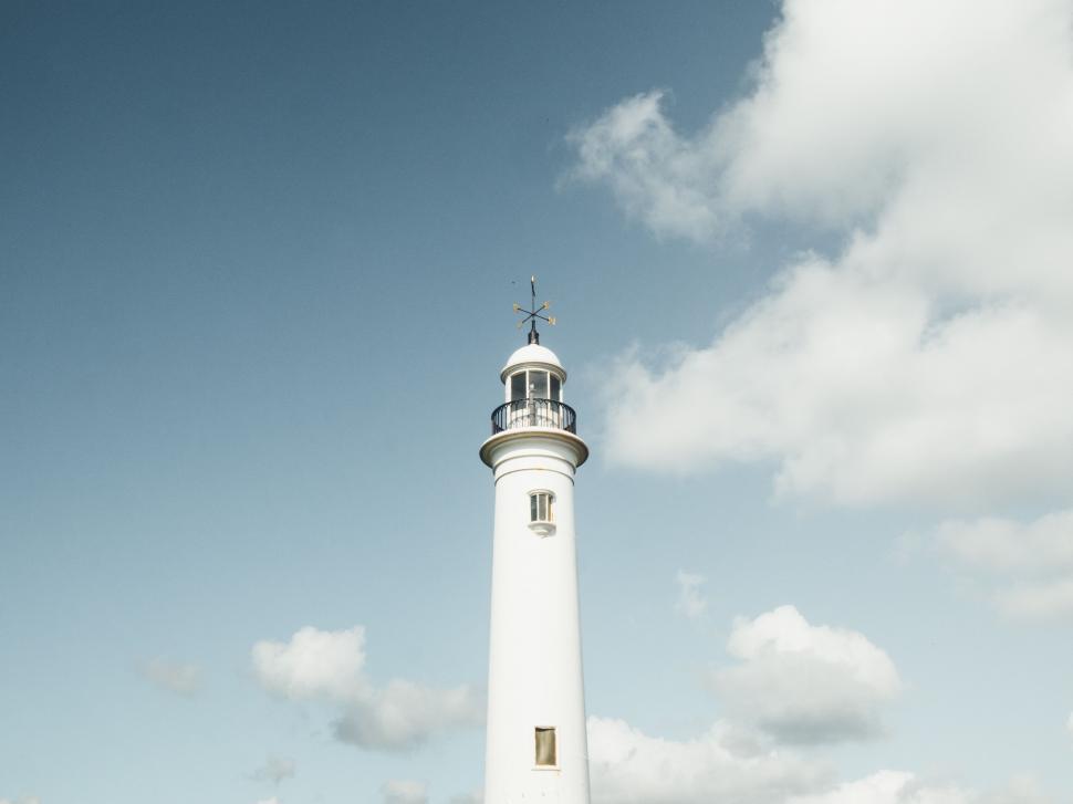 Free Image of A white lighthouse with a weather vane on top 