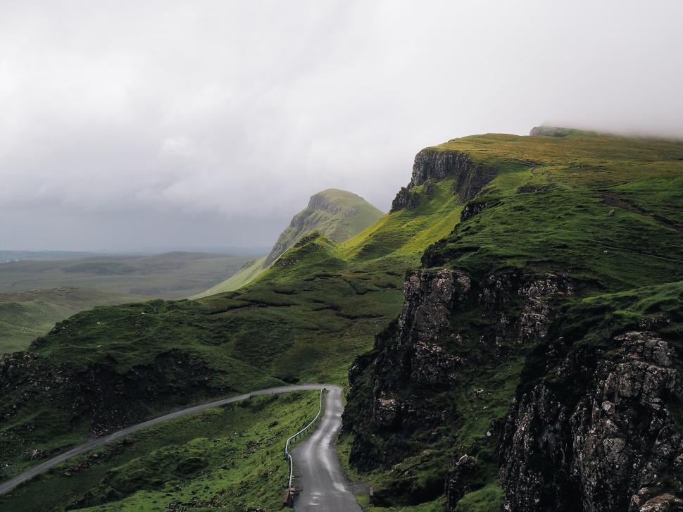 Free Image of A road going through a green valley with quiraing in the background 