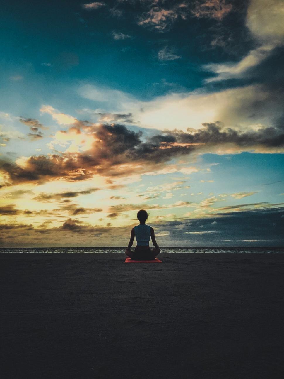 Free Image of A person sitting on a beach 