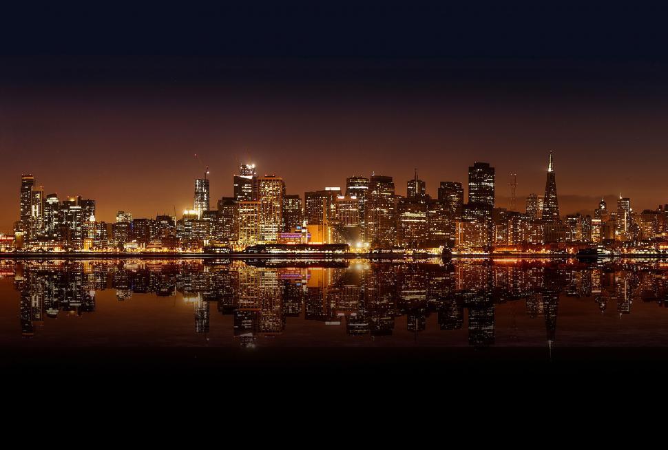 Free Image of A city skyline at night with lights reflecting on water 