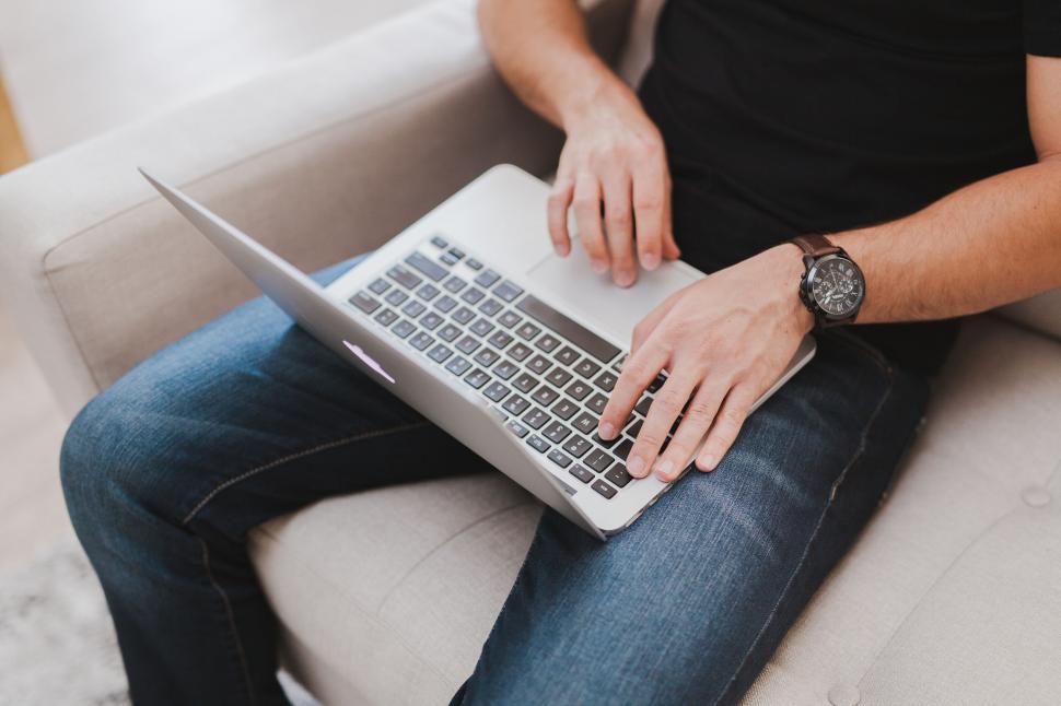 Free Image of A person sitting on a couch using a laptop 