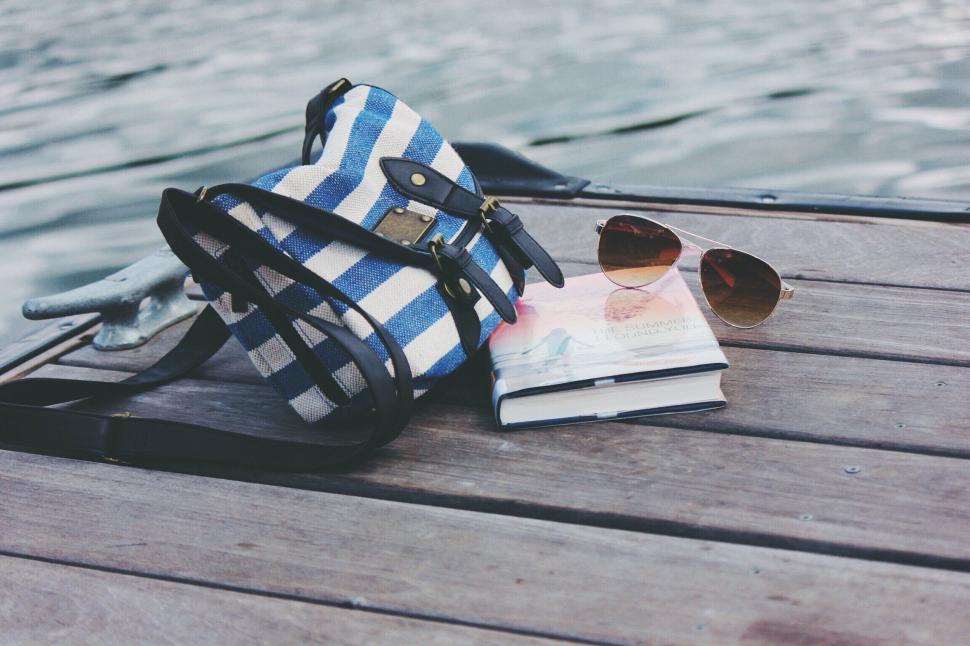Free Image of A bag and sunglasses on a dock 